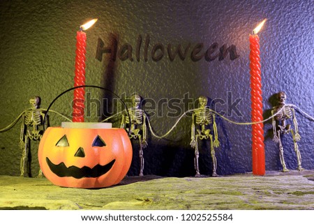 Halloween Pumpkins on old wooden with candle lights and four skeletons and text "Halloween" on background. Happy Halloween Day concept.