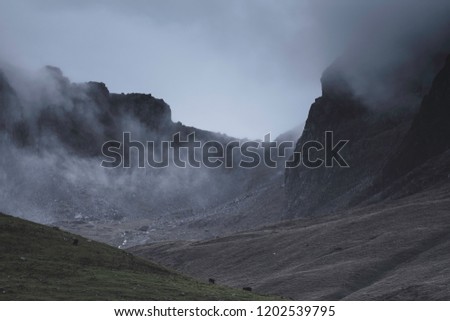 Weather Uk.Dark clouds over mountain peaks in Cumbria, North West England.Dramatic landscape  scene and extreme weather conditions.Fog rolling over mountain ridge.Dark, moody atmosphere . Royalty-Free Stock Photo #1202539795