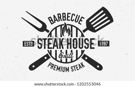 Steak House, barbecue restaurant logo, poster. BBQ trendy logo with barbecue grill , spatula and grill fork. Vector emblem template. Royalty-Free Stock Photo #1202553046