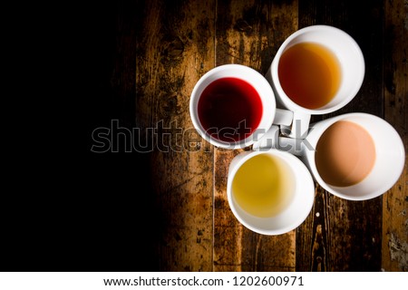 Different types of tea lined up in a grid in cups from light coloured teas through to red and black coloured
