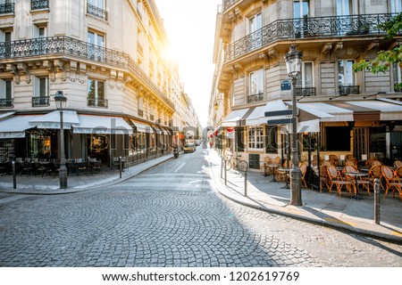Street view with beautiful buildings and cafe terrace during the morning light in Paris Royalty-Free Stock Photo #1202619769