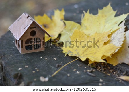 miniature wooden house on a stump, on a background of autumn leaves