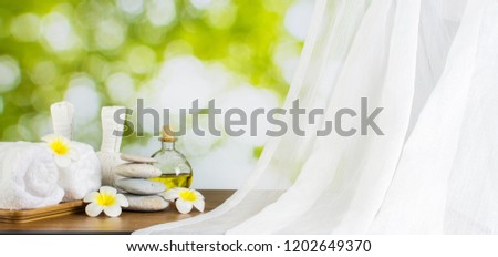 Close up spa composition in wellness center, Towels on massage table in spa salon setting. Spa feet & hand massage compress balls, aromatherapy oil in Nature Bamboo forest in garden with light & bokeh