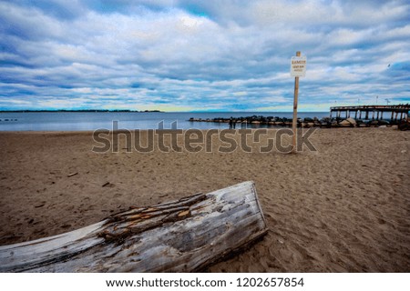 warning sign with fallen wood on the beach with blue sky and cloud
