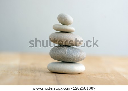 Stone cairn on striped grey white background, five stones tower, simple poise stones, simplicity harmony and balance, rock zen sculptures Royalty-Free Stock Photo #1202681389