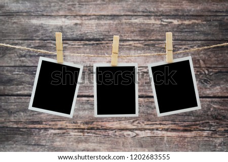 photos hang on a rough rope, fixed with wooden clothespins on a wooden background.