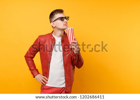 Portrait of vogue young man in 3d glasses, red leather jacket, t-shirt watching movie film, holding cup of soda or cola isolated on bright yellow background. People sincere emotions lifestyle concept