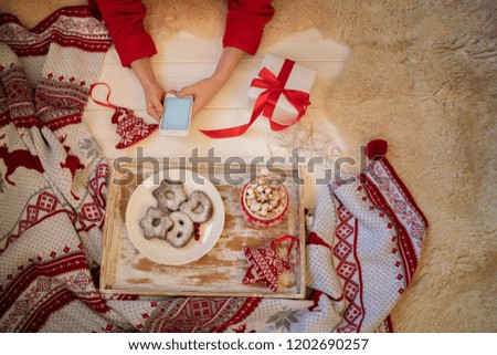Close-up image of female hands using smartphone at home, siting on floor, searching or social networks concept, hipster girl typing an sms message to his friends. Christmas eve. Spending time, holiday