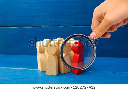 Group people figurines. Society, social group. Herd instinct, management of people. Human resources, workers stand together. Magnifying glass is looking at the Red man stands out from group,