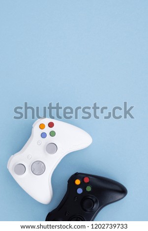 Two joysticks, black and white on a pastel blue background. White and black gamepad are isolated on a pastel blue background. Computer game competition. Gamer concept. Copyspace