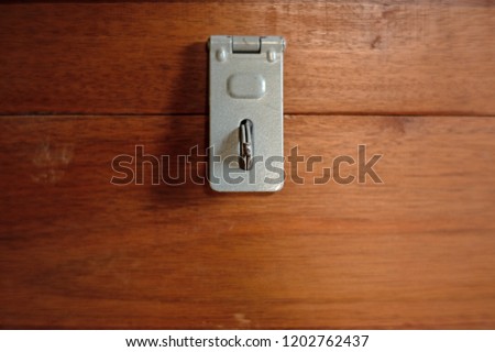 Close up of Metal Hasp staple on wooden box, Key Locking Devices to secure storage. Royalty-Free Stock Photo #1202762437