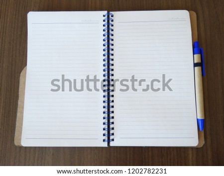 Blank notebook or notepad on wooden background with pen                        