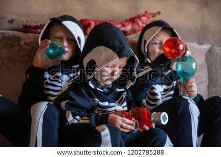 Happy children in carnival costumes, boys with a red crocodile in the garage. Black suit with the image of skeletons. Classic Halloween costume. Happy childhood of children