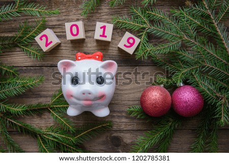 New Year picture with Christmas tree branches and red toys and the symbol of 2019 - pig on a wooden background