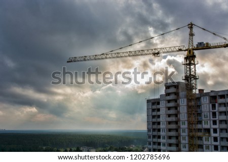 Silhouette of Industrial construction cranes and building site over stormy sky. grunge filter photo