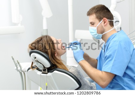Happy dentist working making a dental hygiene to a patient Royalty-Free Stock Photo #1202809786