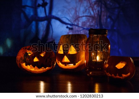 orange pumpkins with scary faces and candles lies on the table in front of dark background. Halloween celebration concept