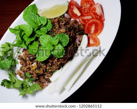 Top view picture of spicy minced pork salad on white plate.