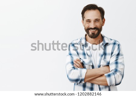 Lonely male farmer seeking woman to merry her, posting picture in social media. Portrait of happy handsome man with beard and moustache holding hands crossed in confident pose and smiling broadly