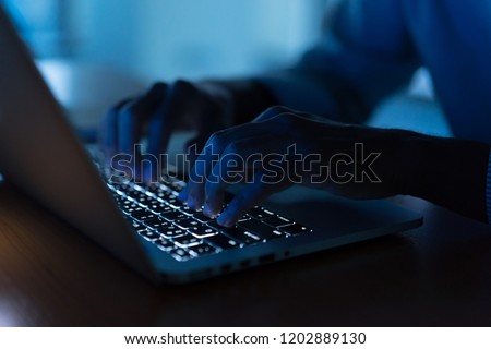 close up engineer employee man hand typing keyboard input code for register system structure or unlock password on laptop in dark operation room for cyber security and work from home concept