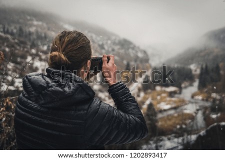 A man taking a photo in the mountains during an autumn snow storm. 