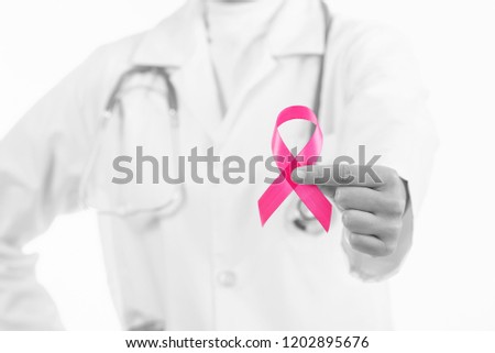 Doctor woman holding pink ribbon, supporting symbol of breast cancer awareness and international women day campaign.