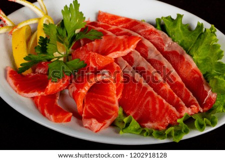 Sliced salmon sashimi with parsley and lemon