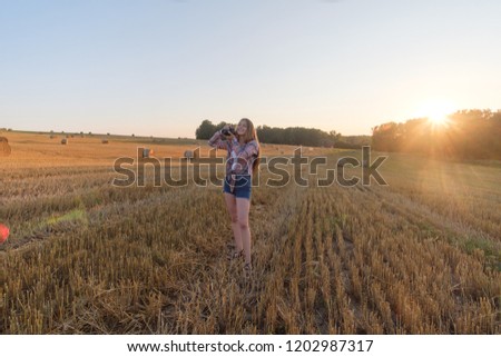 young European girl with a camera in the summer evening at sunset taking pictures