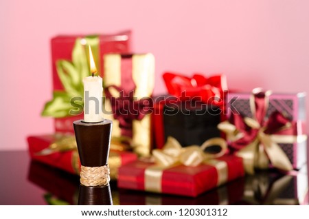Candle and gifts boxes against pink background