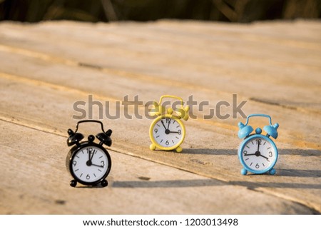 Three small alarm retro clocks on wooden surface. Autumn abstract photo.  Daylight saving time.