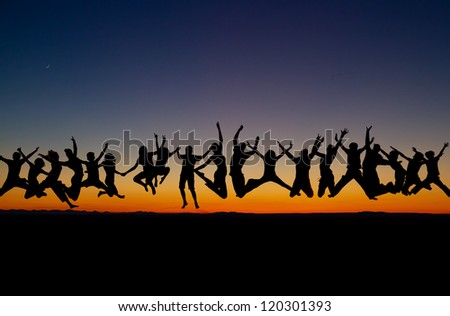 silhouetted large group of teens jumping after sunset