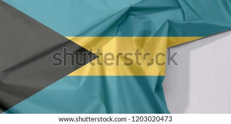 Bahamas fabric flag crepe and crease with white space, triband of aquamarine (top and bottom) and gold with the black chevron aligned to the hoist-side.