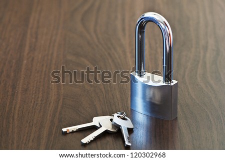 closed padlock and key`s on the brown table