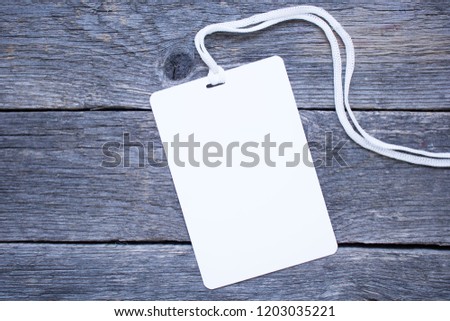 blank white badge on a rope for advertising or text on a wooden table background. Template for ID. Mock-up for branding identity for designers. Top view.