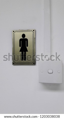 Symbole of ladies toilet with light switch.