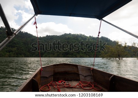 Traditional wooden boat in a picture rainy season at Prakarnchon Khun Dan Dam, Nakhon Nayok, Thailand