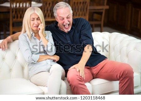Man having a good laughter while his wife cries Royalty-Free Stock Photo #1203118468