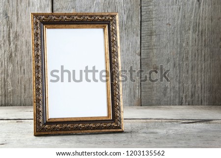 Empty brass picture frame on old wooden gray textured background. Home decor and copy space for text.  