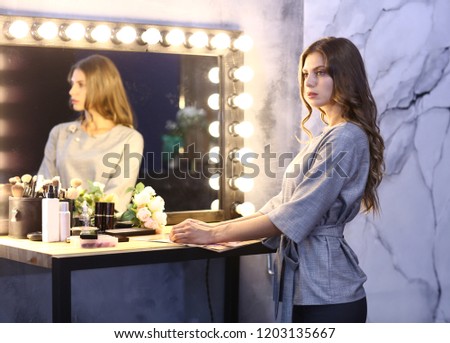 fashion model girl in gray jacket with mirror on blue wall background close up photo