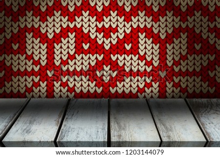 Surface of wooden plank against red seamless knitted pattern snowflakes