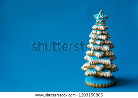 Blue chirstmas tree gingerbread cookie on blue background. Holidays food and decoration concept