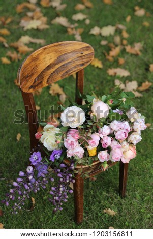Gorgeous bouquet of roses on vintage wooden child chair on leaves, grass background, autumn scene, daylight, vertical
photo