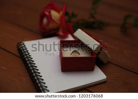 proposal marriage: engagement ring, red rose and word "yes" written on a paper