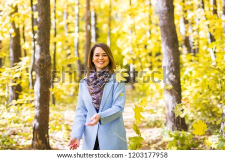 Autumn, fun and delight concept - Young beautiful woman throwing bouquet of leaves