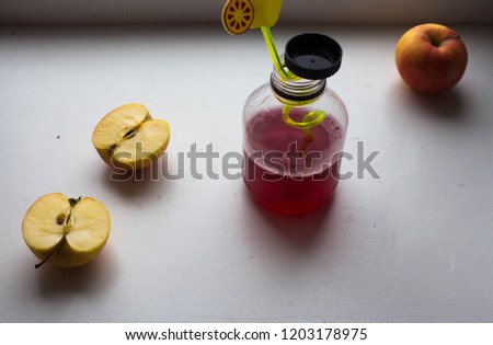 a bottle with juice and apples on the white background