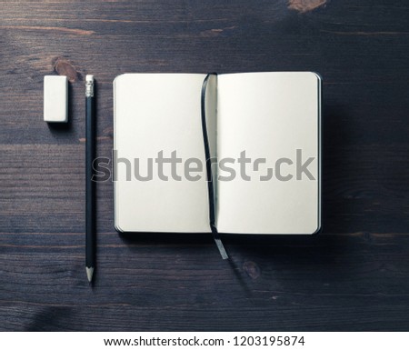 Blank opened notebook, pencil and eraser on wooden background. Template for graphic designers portfolios. Flat lay.