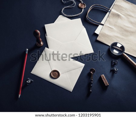 Blank envelopes with wax seal, stamp and vintage stationery on black paper background.