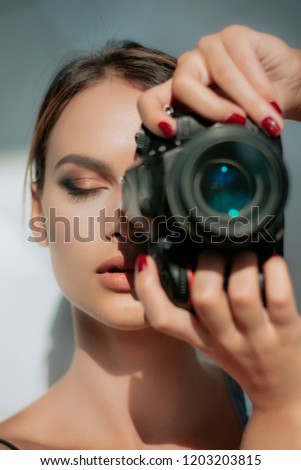 Portrait of a photographer covering her face with the camera. Isolated on a white background. Photographer, Camera, Women. Professional female photographer