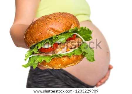 Pregnant woman with belly is holding a burger - unhealthy eating in pregnancy concept