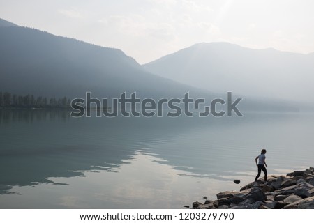 Photograph of a lake with a person walking. Taken in British Columbia, Canada.